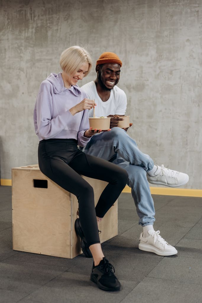 Two individuals enjoying a nutritious meal together in a casual setting indoors.